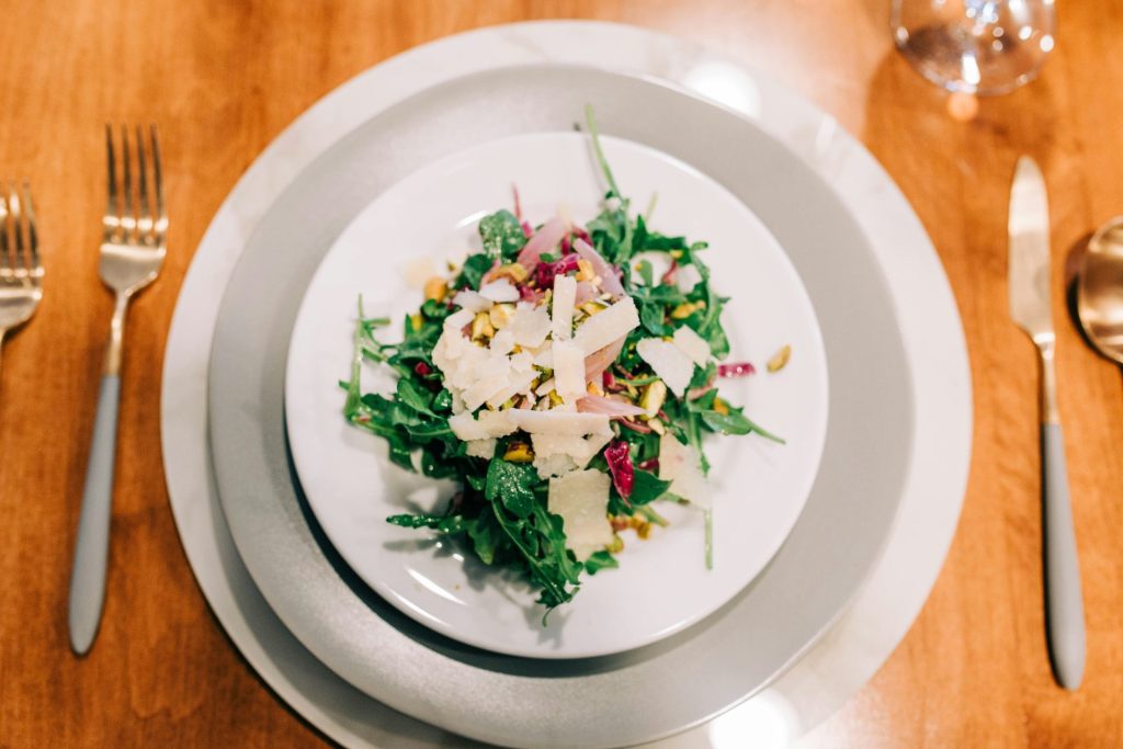 a white plate topped with a salad on top of a wooden table